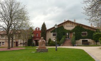 a large building with a statue in front of it and a red brick building behind it at Hotel El Rancho