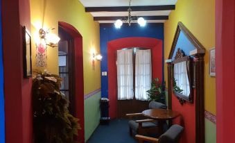 a brightly colored room with a blue carpet and a red ceiling , featuring a small dining table , chairs , and a door at Grand Hotel