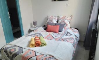 a bed with a colorful blanket and three rolled towels on top of it , creating a cozy and inviting atmosphere at Vichy