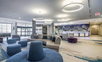 a modern hotel lobby with various seating options , including couches and chairs , as well as a bar at SpringHill Suites Oklahoma City Downtown/Bricktown