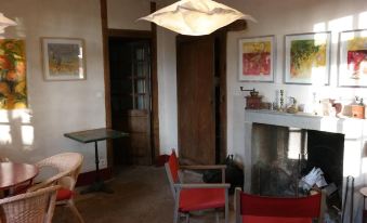 a cozy living room with a fireplace , two chairs , and a painting on the wall at Le Petit Paris