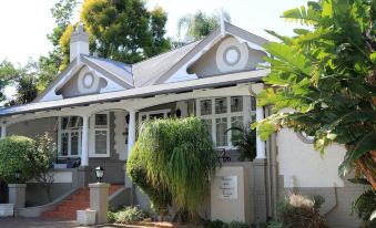 a large , white house with a gray roof and stone steps leading up to the front door at Oxford Lodge Vryheid