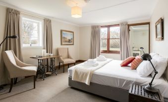 a hotel room with a large bed , two chairs , and a window overlooking the city at Ratho Farm