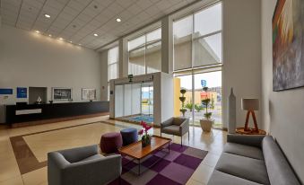 a modern living room with a couch , chairs , and a coffee table in front of a large window at City Express by Marriott Nogales