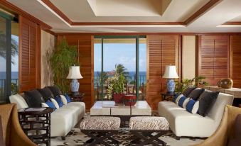 a living room with a couch , coffee table , and two lamps overlooking the ocean through a window at Grand Hyatt Kauai Resort and Spa