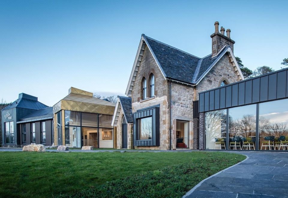 a large stone house surrounded by a grassy field , with a fountain in the background at Isle of Raasay Distillery