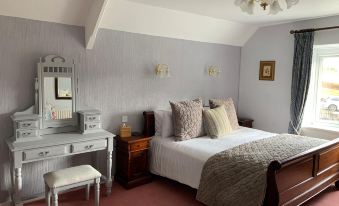a cozy bedroom with a white bed , a desk , and a mirror , decorated with elegant furniture and lighting at Lydgate House Hotel