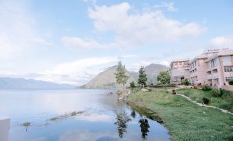 a serene lake with a small island in the middle , surrounded by lush greenery and mountains in the background at Portola Grand Renggali Hotel Takengon