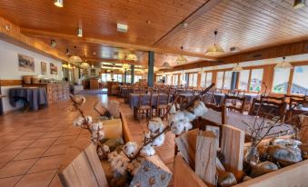 a large room with wooden tables and chairs , along with stuffed animals on the tables at Hotel Roc et Neige