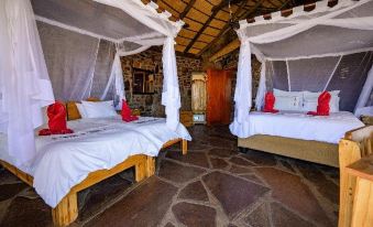 a room with two beds , one on the left and one on the right , covered by white mosquito netting at Canyon Lodge