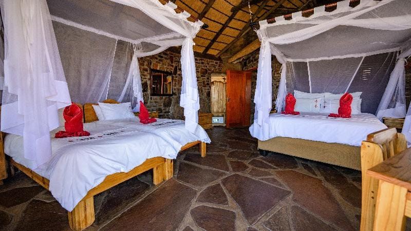 a room with two beds , one on the left and one on the right , covered by white mosquito netting at Canyon Lodge