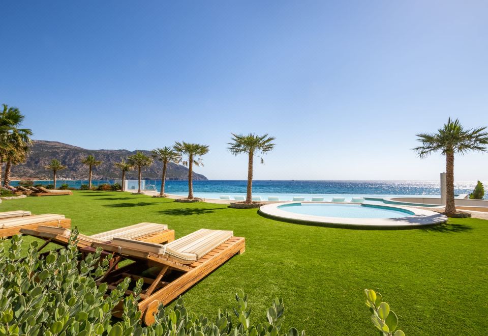 a serene outdoor setting with a pool , sun loungers , and palm trees under a clear blue sky at Konstantinos Palace