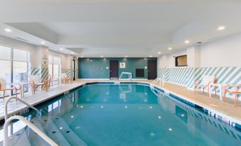 a large swimming pool with a white and blue striped wall is surrounded by lounge chairs at Holiday Inn Allentown-Bethlehem