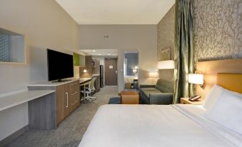 a modern hotel room with a bed , desk , and couch , as well as various pieces of furniture at Home2 Suites by Hilton Springdale Cincinnati