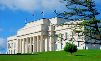 a large white building with columns and american and british flags flying in front of it at Poenamo Hotel