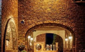 a brick building with an arched entrance and a courtyard , illuminated by lights at night at Loftsome Bridge Hotel