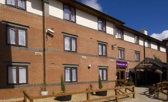 a brick building with a purple sign and wooden railings in front of it , under a blue sky at Premier Inn Gillingham Business Park