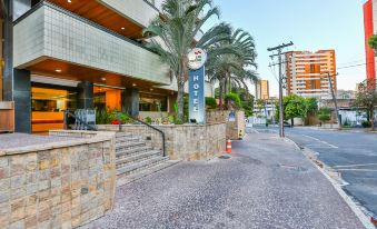 a hotel with a sign on the front , located next to a street with palm trees at San Marino Suites Hotel by Nobile