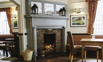 a cozy living room with a fireplace , a dining table , chairs , and pictures on the wall at The Bulls Head