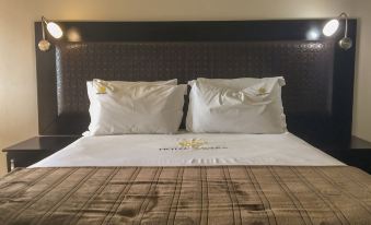 a hotel room with a king - sized bed and two white pillows on the brown comforter at Hotel Savera