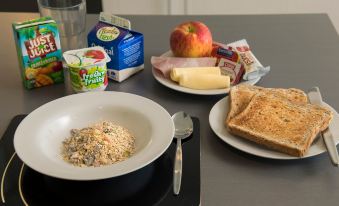 a table with a bowl of oatmeal , a sandwich , a plate of bread , and a glass of milk at Quest Highbrook