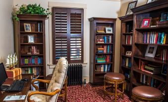 a cozy living room with wooden furniture , including a couch , chairs , and bookshelves filled with books at Chamberlin Inn