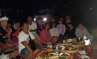 a group of people gathered around a table in the dark , posing for a photo at Peisanae Faikeng Resort