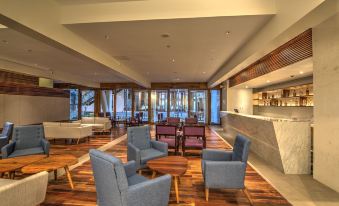 a large , well - lit room with wooden floors and furniture , including two blue armchairs , a coffee table , and several chairs at Hotel Somadevi Angkor Resort & Spa