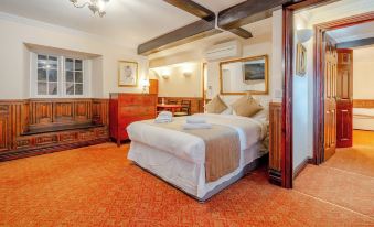 a large bed with a white comforter and brown blanket is in the middle of a room with orange carpet at The Crown Hotel