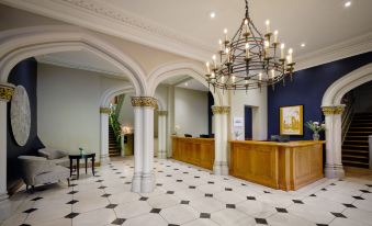 a large hotel lobby with a check - in desk , a reception desk , and a staircase leading to the second floor at Delta Hotels Breadsall Priory Country Club