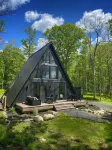 A modern A-frame, nestled in the woods with relaxing outdoor spaces and firepit.