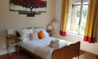 a cozy bedroom with a large bed , white sheets , and a red tree painting on the wall at La Roseraie