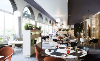 a restaurant with a dining table and chairs , as well as several potted plants placed around the room at Novotel Toulouse Centre Compans Caffarelli