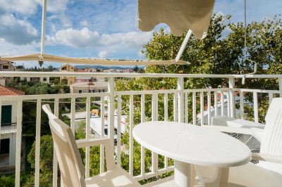 a white table and chairs are set up on a balcony with an umbrella overhead at Hotel Summery