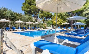 a large outdoor swimming pool surrounded by lounge chairs and umbrellas , providing a relaxing atmosphere for guests at Hotel Cala Murada