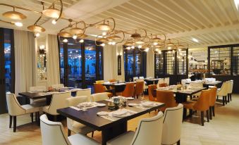 a restaurant with several dining tables and chairs , some of which are covered in white tablecloths at Camiral Golf & Wellness - Leading Hotel of the World