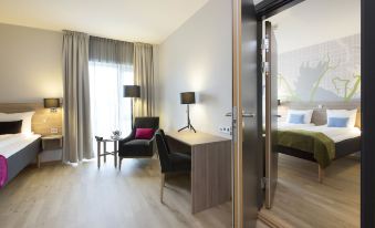 a modern hotel room with a large bed , desk , and chair , as well as a balcony view at Thon Partner Elgstua Hotel