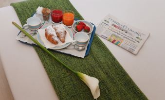 a table with a tray of food , including croissants , strawberries , and a cup of tea at Hotel Forum