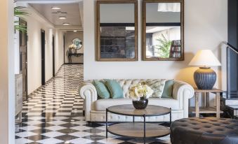 a living room with a white couch , black and white checkered floor , and two large mirrors on the wall at Salles Hotel Aeroport de Girona