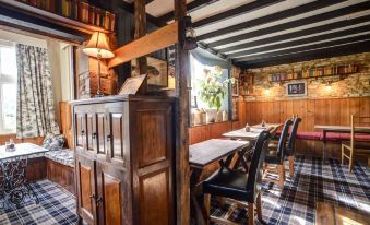 a dining room with a wooden table and chairs , surrounded by a bookshelf filled with books at Thames Head Inn