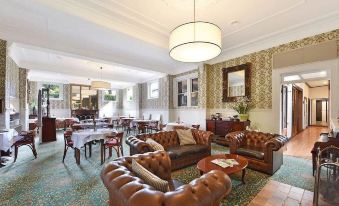 a spacious living room with multiple couches and chairs arranged around a dining table , creating a cozy atmosphere at Hotel Etico at Mount Victoria Manor