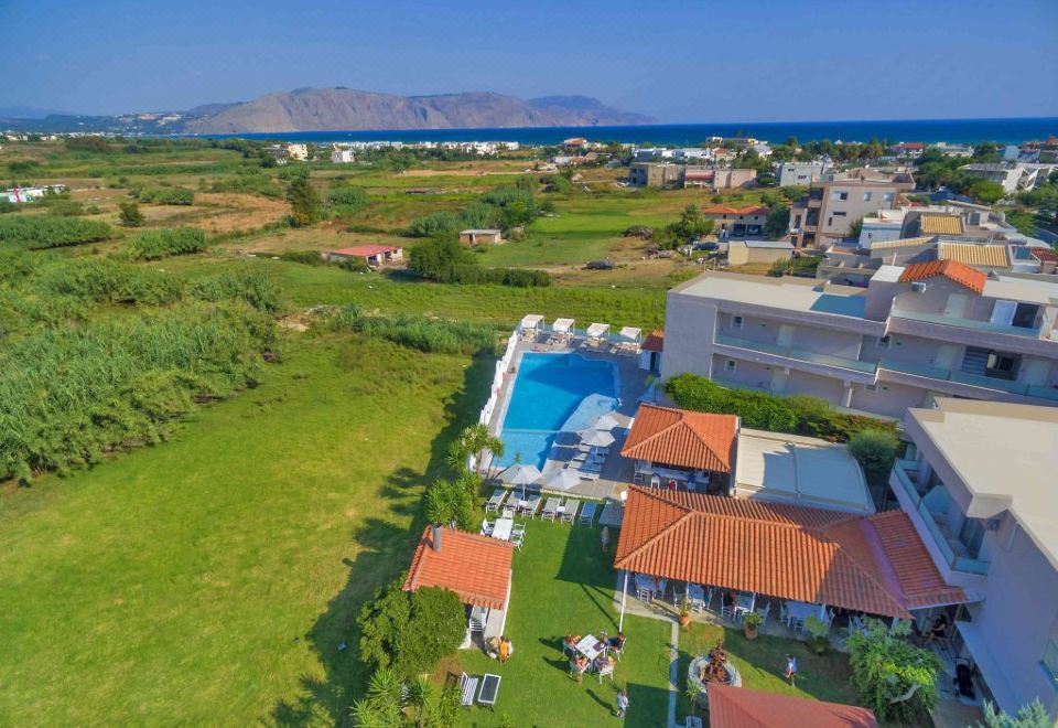 aerial view of a large villa surrounded by green fields , with a swimming pool in the background at Apollo Apartments