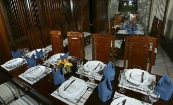 a dining room with a long wooden table set for a meal , complete with plates , forks , knives , cups , and silverware at Hotel du Lac Macae