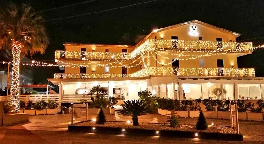 a large building with a string of lights on it and a few potted plants in front at Victoria Hotel