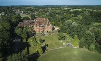 aerial view of a large brick building surrounded by trees and grass , located in a rural area at New Place