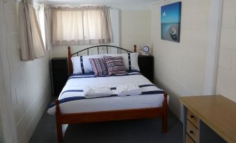 a neatly made bed with a wooden headboard and blue and white striped bedding in a small room at Sailors Rest