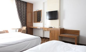 a modern hotel room with a white bed , wooden desk , and tv , along with curtains and a window at Mostar Hotel