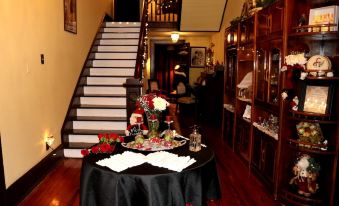 a dining room with a table set for a formal dinner , surrounded by chairs and a staircase at Whole Hearts Bed and Breakfast
