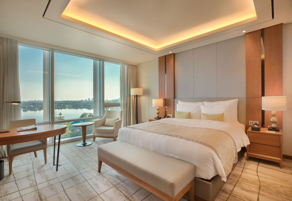 a large bedroom with a bed , a chair , and a window overlooking a body of water at Lotte Hotel Yangon