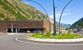 a city street with a large building in the background , surrounded by cars and traffic lights at Matterhorn Inn